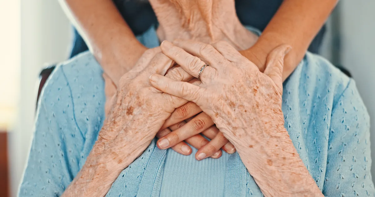 Pflegerin hält Hand einer Seniorin