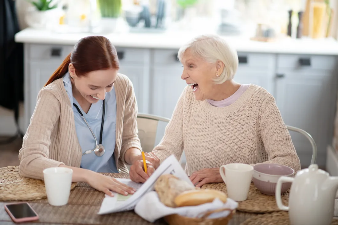 Pflegerin und Seniorin lachen gemeinsam – Care for You im Alltag